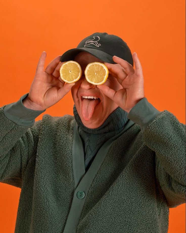 a man holding up oranges as eyes